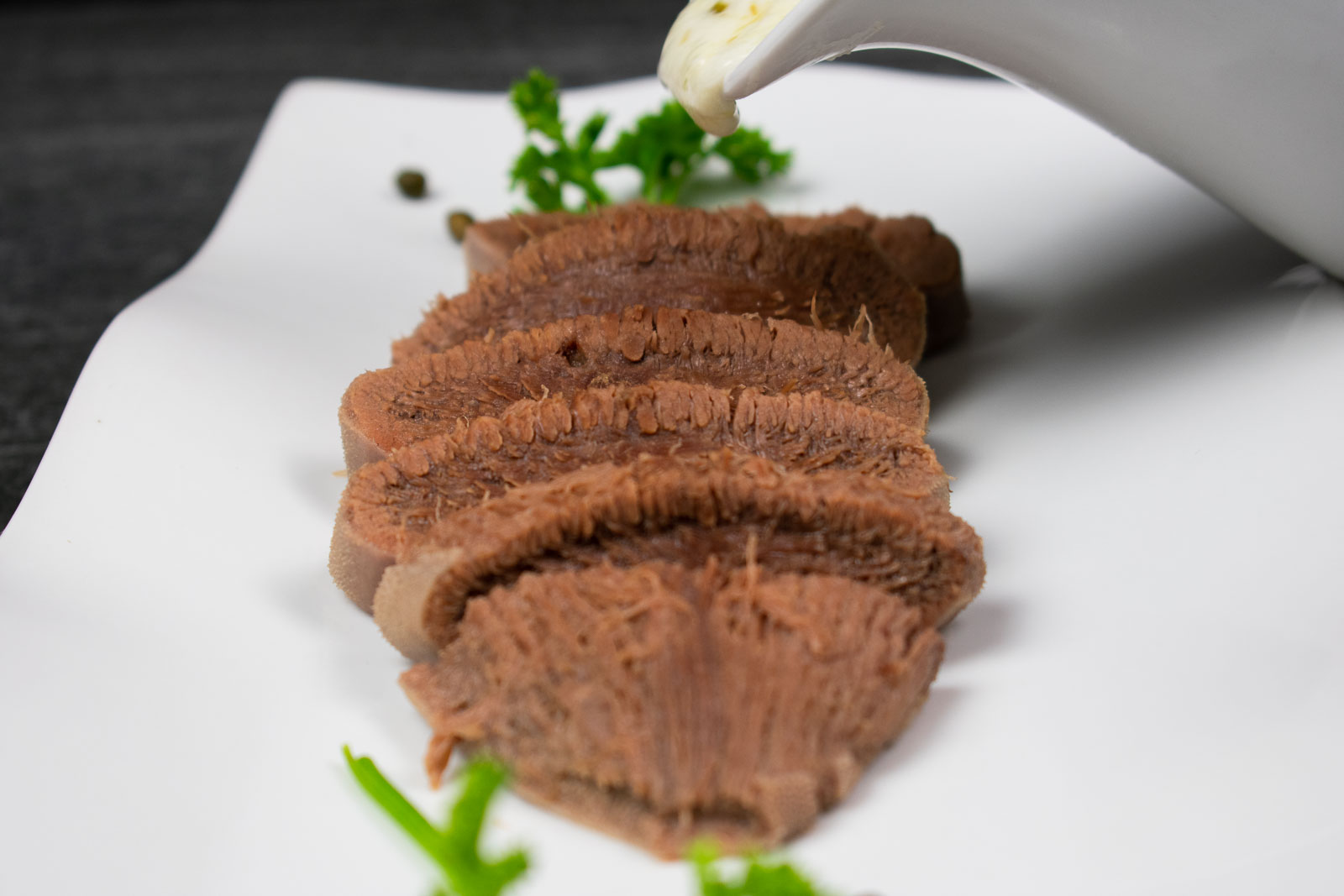 Tender Beef Tongue is covered in white wine creamy sauce with Capers.